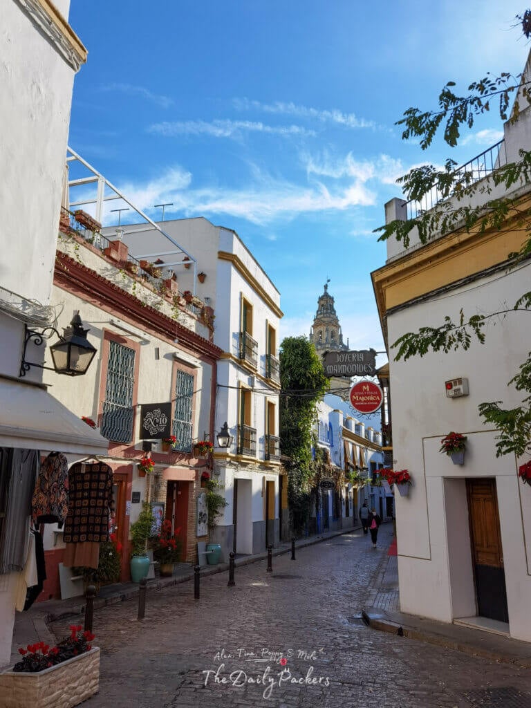 Rue pittoresque dans le quartier juif de Cordoue avec une architecture andalouse traditionnelle et une vue sur le clocher.