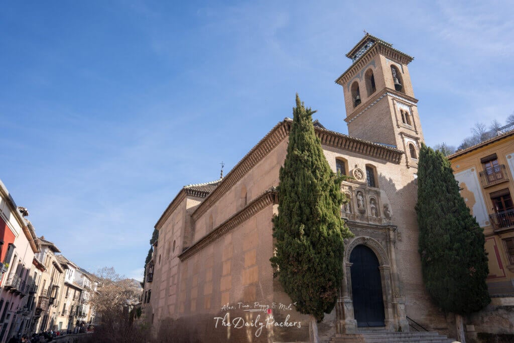 Vue de l'Iglesia de San Gil y Santa Ana à Grenade, une belle église avec une tour en brique et des cyprès près de la rivière Darro.