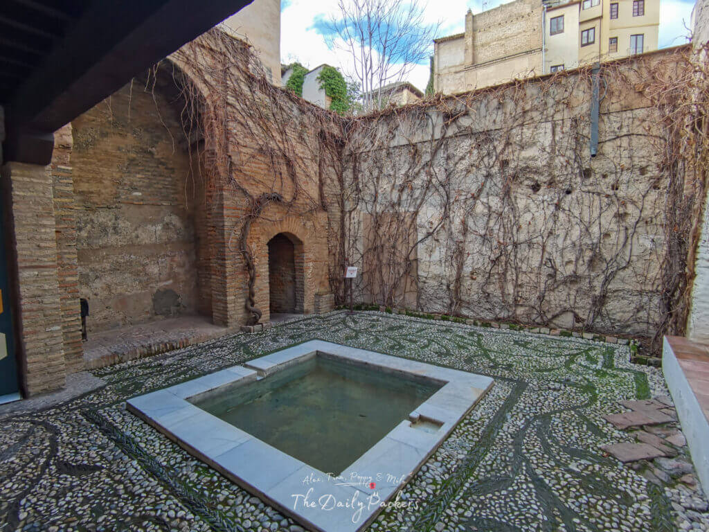 Ancient stone chamber of El Bañuelo, Granada’s historic Arab baths, with horseshoe arches and star-shaped skylights.