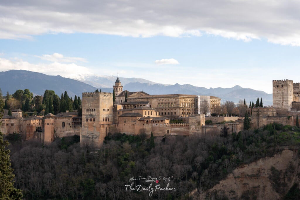 Majestic view of the Alhambra in Granada with its towers and palaces framed by the Sierra Nevada mountains.