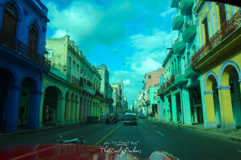 Colorful old colonial buildings and vintage cars along a lively street in Havana, Cuba.