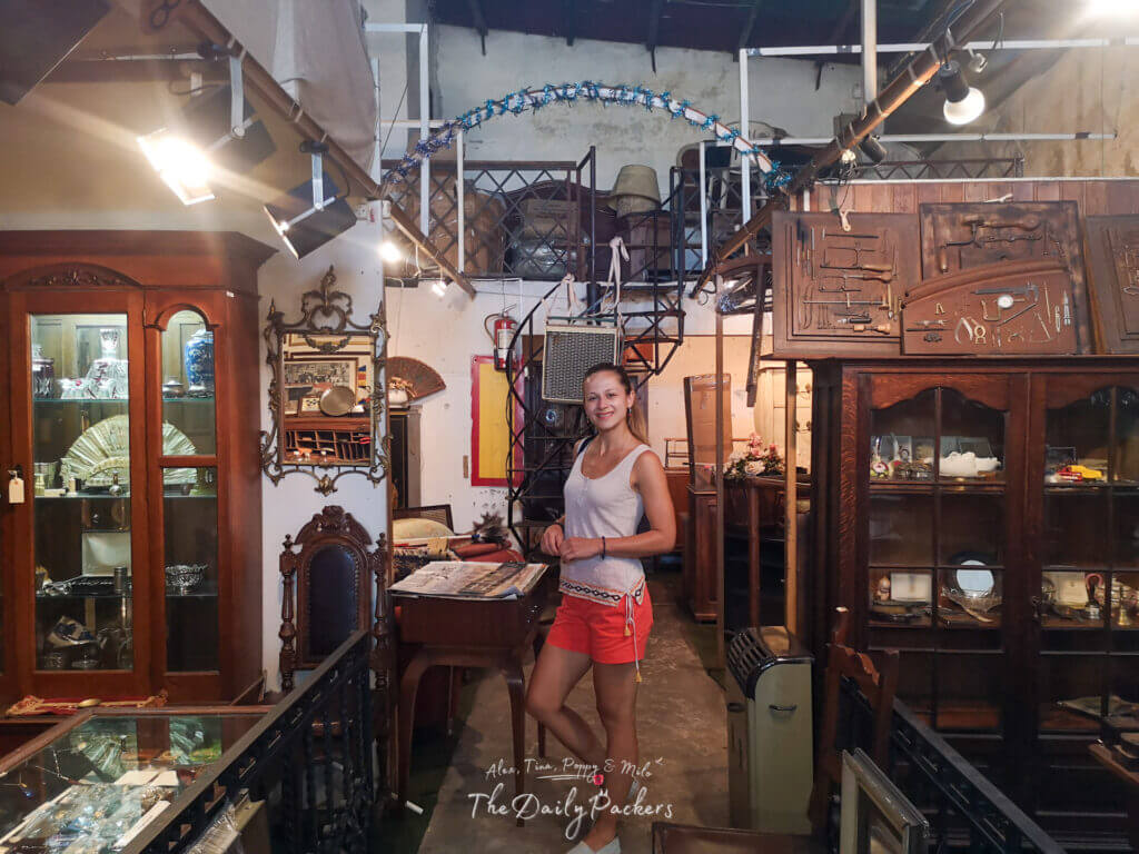 Traveler standing inside a vintage antique shop in Montevideo surrounded by old furniture, mirrors, and collectibles.