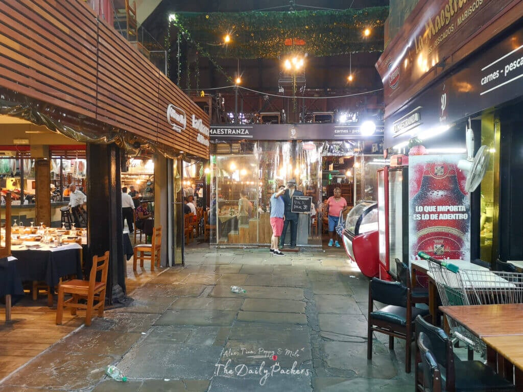 Inside Mercado del Puerto in Montevideo, lined with traditional parrilla restaurants and warm lighting.