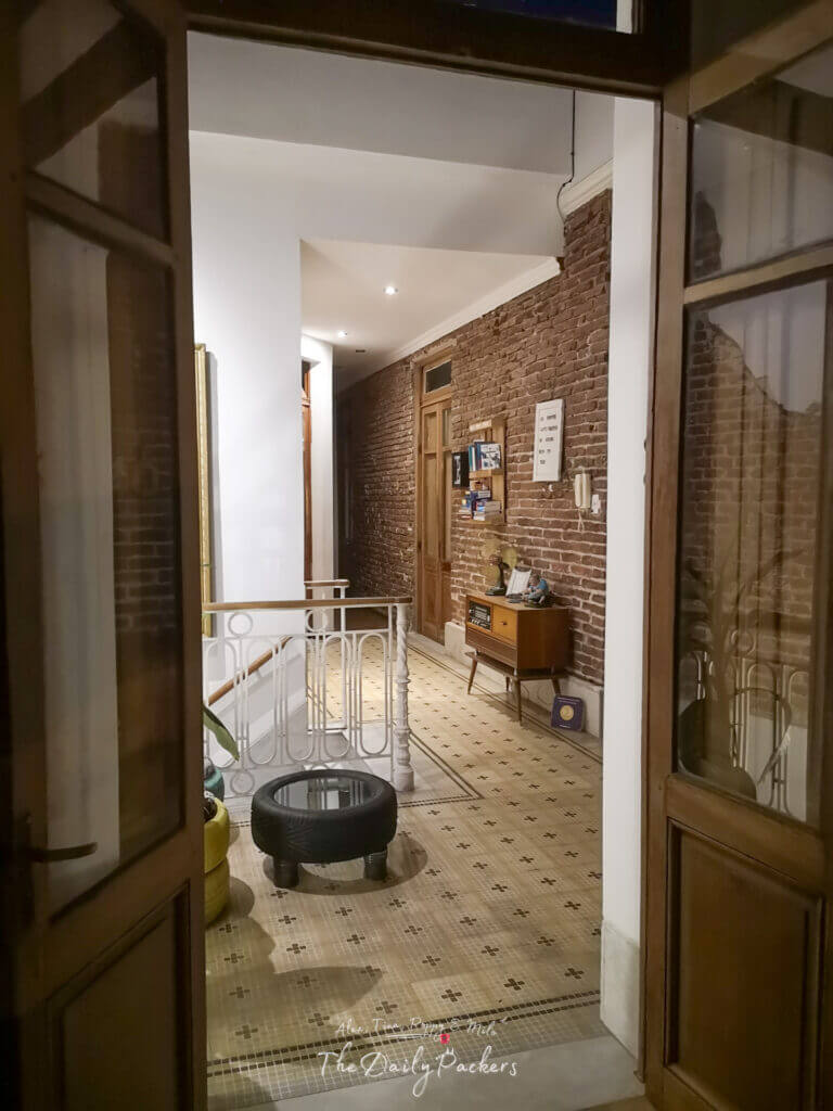 Interior of a charming Montevideo guesthouse with brick walls, tiled floors, and a vintage console in the hallway.
