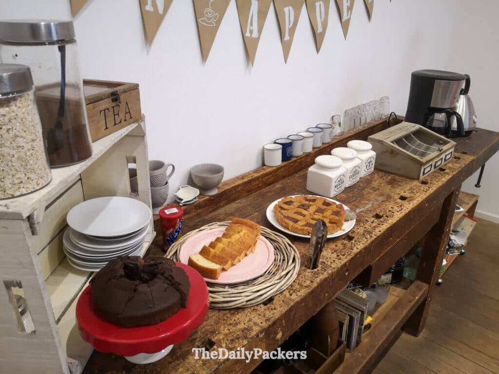 Présentation du petit-déjeuner avec des gâteaux faits maison, du thé et du café servis sur une table en bois vintage avec une décoration chaleureuse.