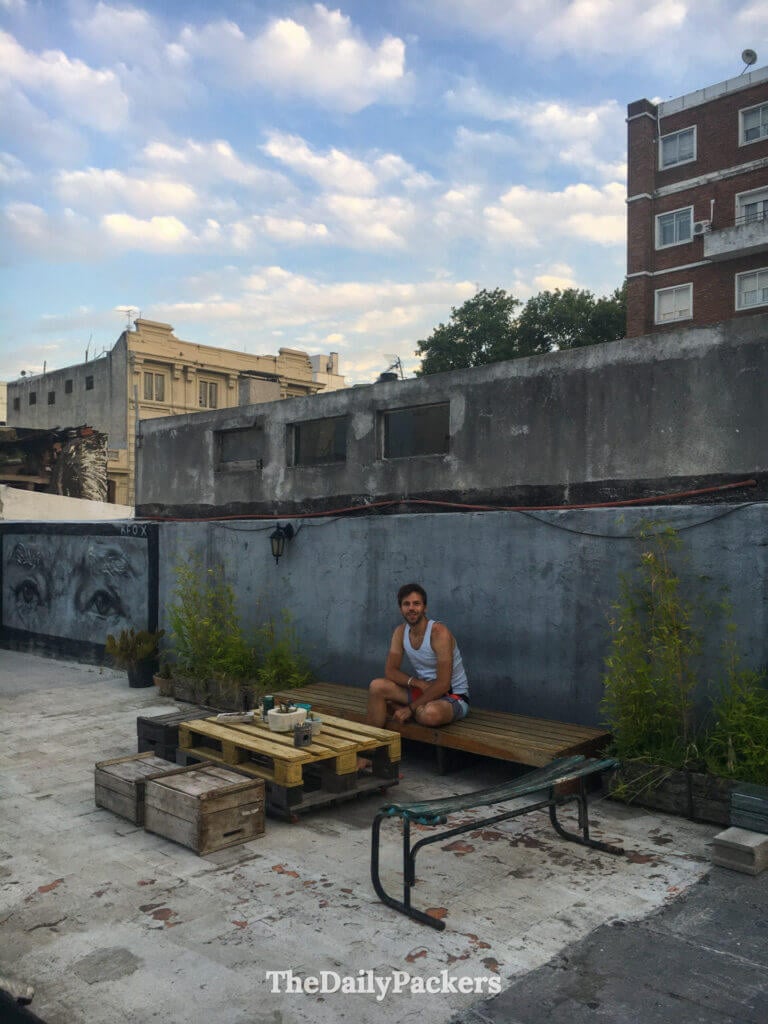 Voyageur se détendant sur la terrasse sur le toit entouré de fresques, de plantes et d'une vue sur le ciel ouvert chez Mario.