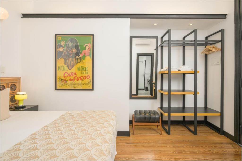 Modern boutique room at Fauna Montevideo featuring a minimalist design, retro movie poster, and open wardrobe.