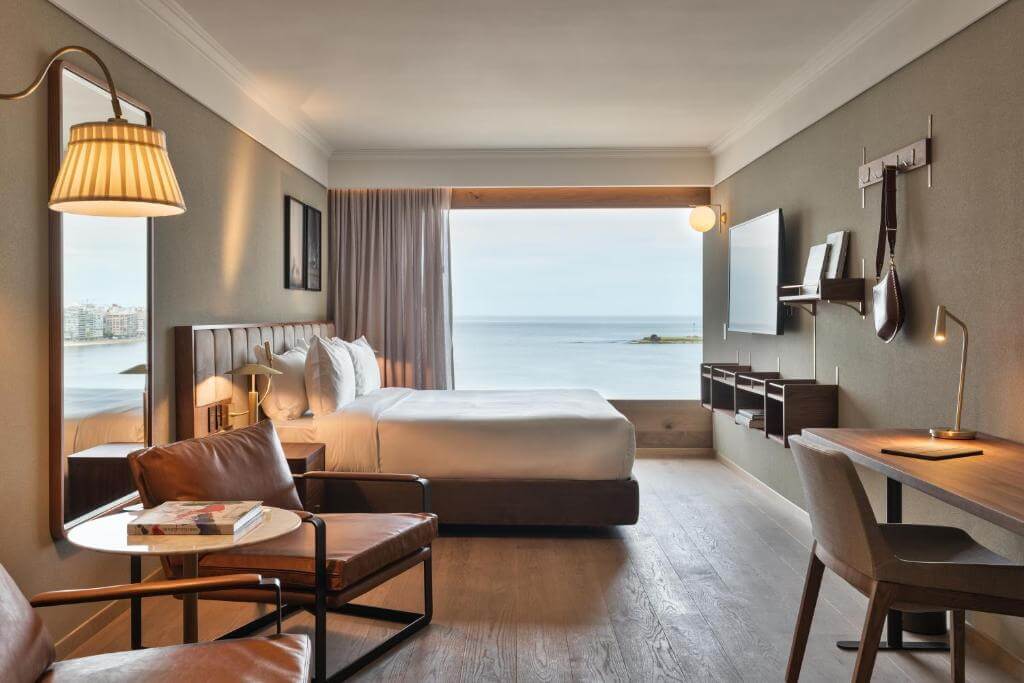Elegant ocean-view room at Costanero Montevideo with floor-to-ceiling windows, stylish furniture, and a relaxing ambiance