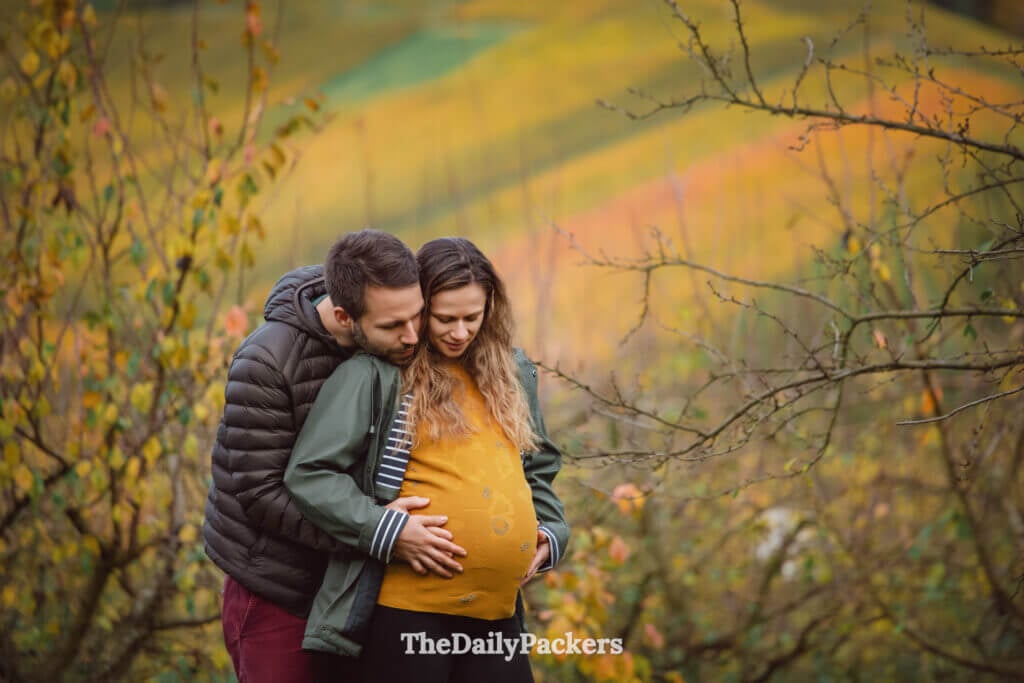 Expecting couple embracing tenderly in an autumn field with golden leaves in the background. It also represent travelling after loss after the stillbirth of Poppy.