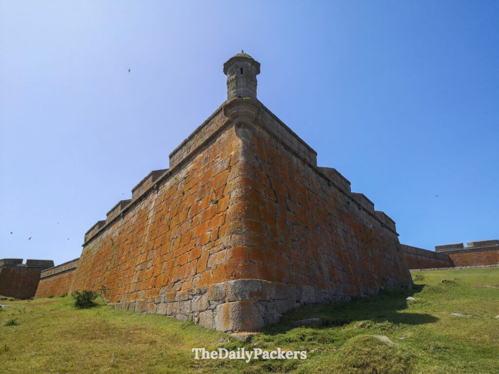 Vue d'angle de la forteresse de Santa Teresa montrant ses massifs murs de pierre orange sous un ciel bleu dégagé