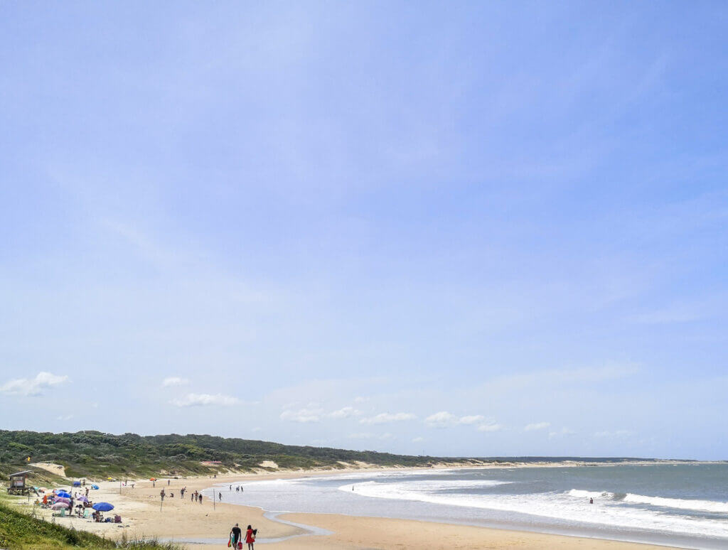 Golden sandy beach inside Santa Teresa National Park with gentle waves and people enjoying the sunny day.