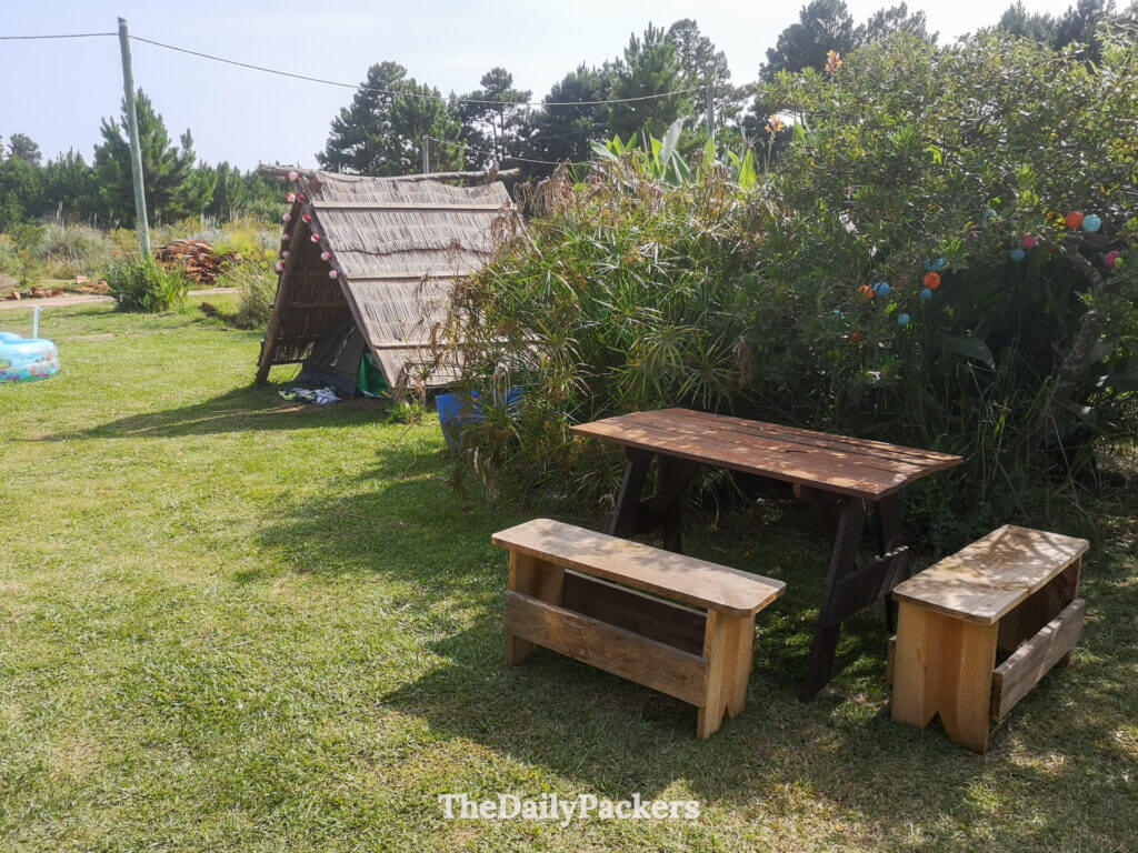 Zone de camping au mini camping La Girada à Punta del Diablo avec une tente couverte et une table en bois