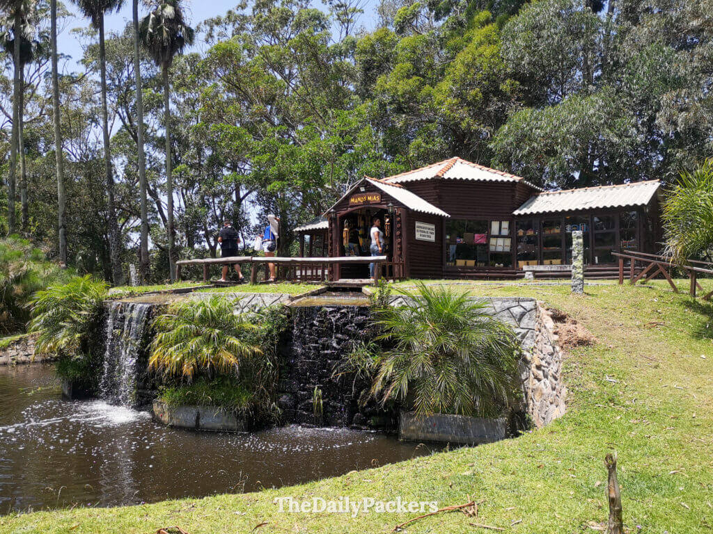 Wooden souvenir shop surrounded by palm trees and a small waterfall in Santa Teresa National Park.
