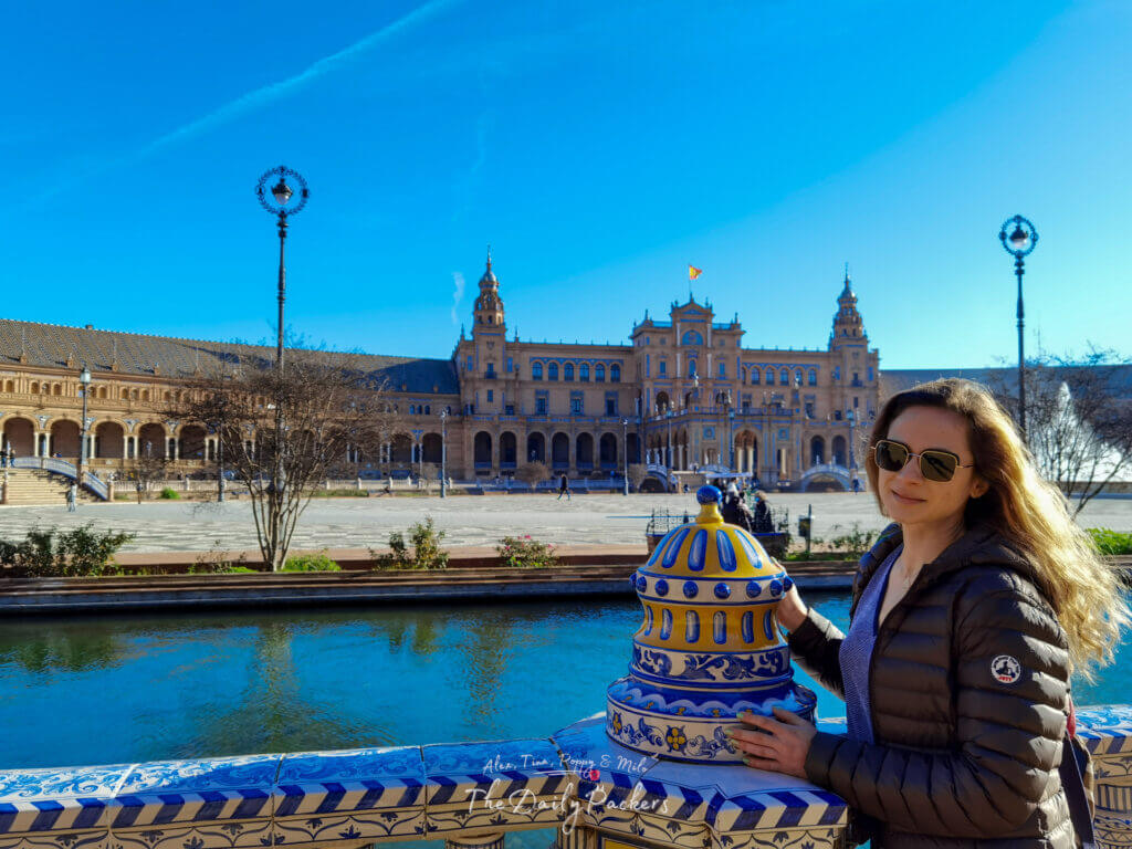 Une femme profitant d'une matinée ensoleillée sur la Plaza de España à Séville, debout près des balustrades en céramique bleue et jaune.