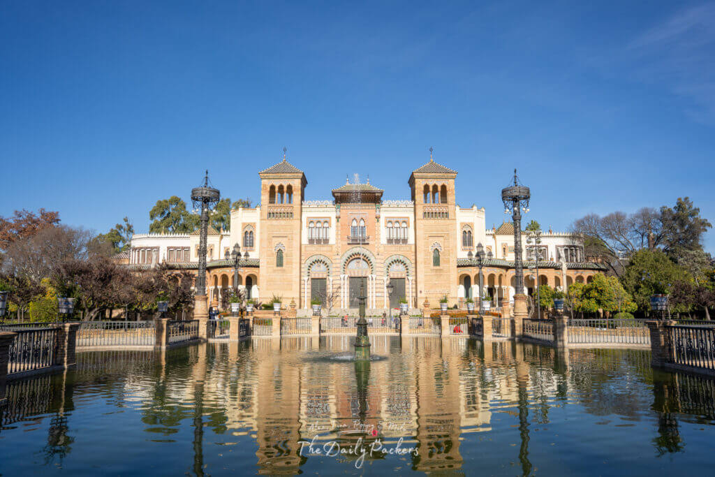 Majestueux bâtiment de style mudéjar de la Plaza de América de Séville se reflétant parfaitement sur l'étang immobile du Parque de María Luisa.