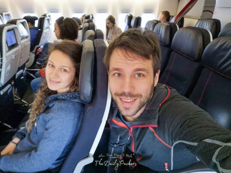 Couple seated together on a plane, smiling as they finally continue their journey after a delay and going to have the cheapest fight ticket of their lives