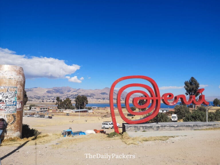 Large red Perú sign overlooking Lake Titicaca and mountain scenery at the Peru–Bolivia border.