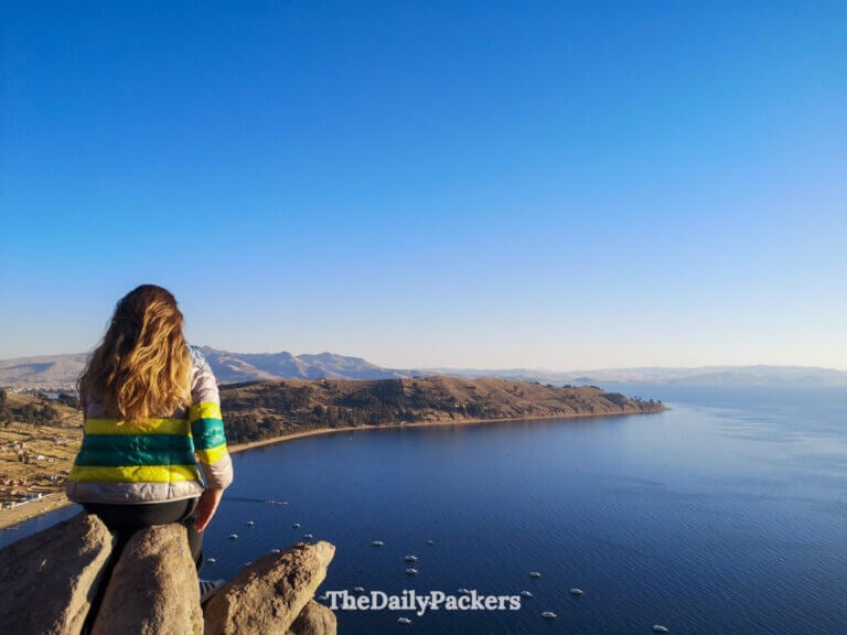 Woman facing the panoramic view of Lake Titicaca from Cerro Calvario during a calm late-afternoon moment in Copacabana in Bolivia