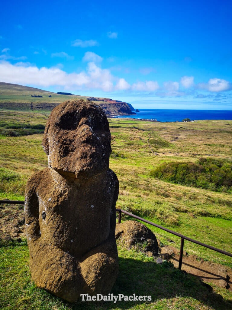 Tukuturi moai statue at Rano Raraku, Easter Island, unique for its kneeling human-like posture, overlooking vast green plains and the Pacific coastline.