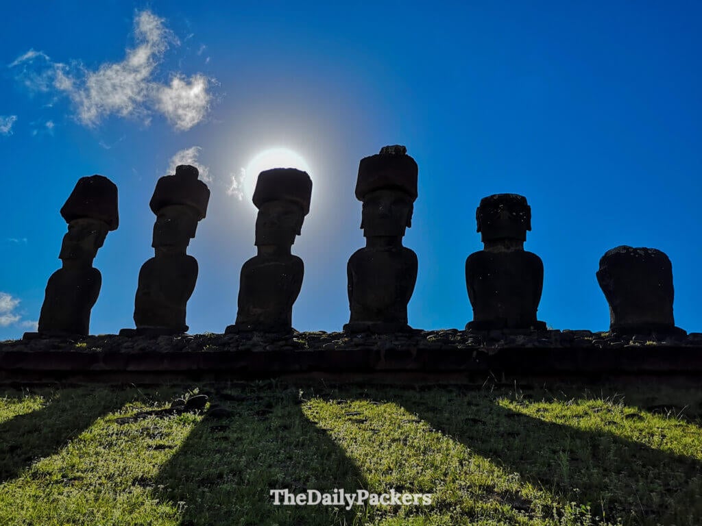 Silhouetted moai statues at Anakena Beach on Easter Island during the afternoon with the sun revealing their shadows in front