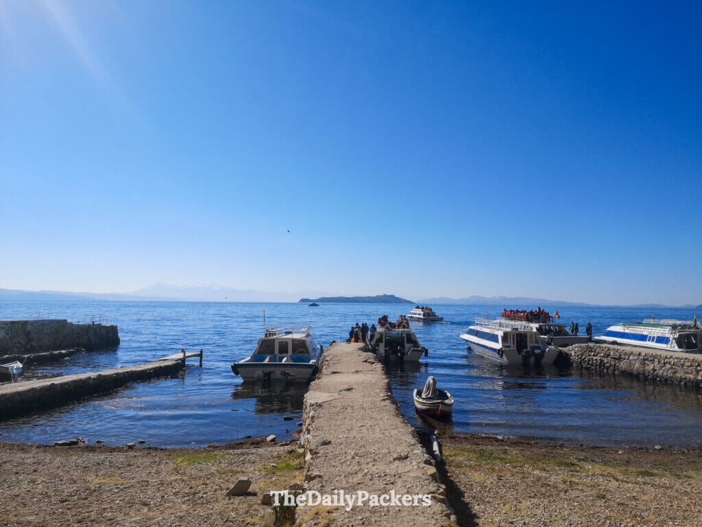 boats lined along the small pier on Copacabana with lake titicaca and the bolivian mountains in the distance