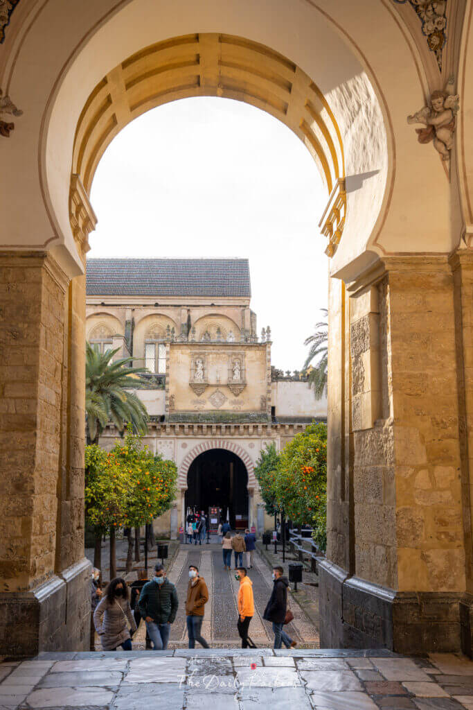 Entrée cintrée encadrant la cour des orangers avec des visiteurs marchant sous les orangers vers la mosquée-cathédrale de Cordoue