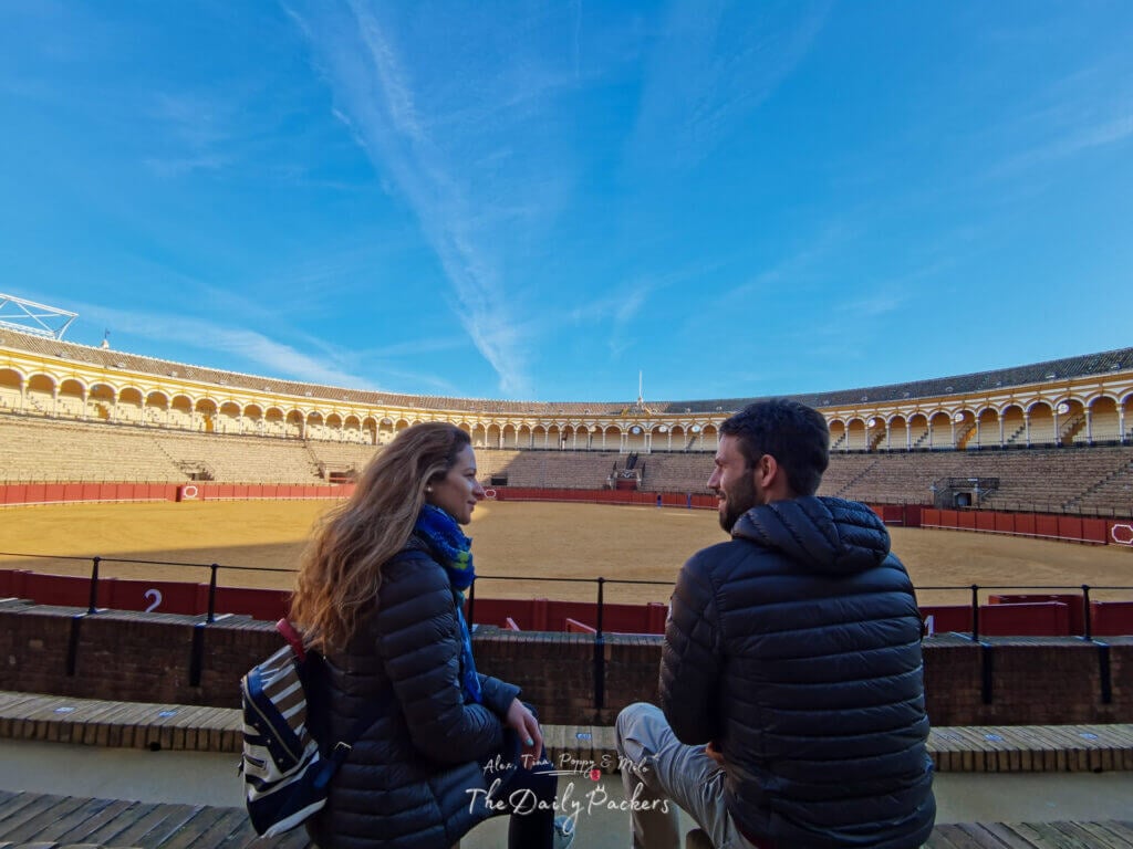 Couple sitting in the front rows of Plaza de Toros, overlooking the grand bullring and its elegant Andalusian arches.