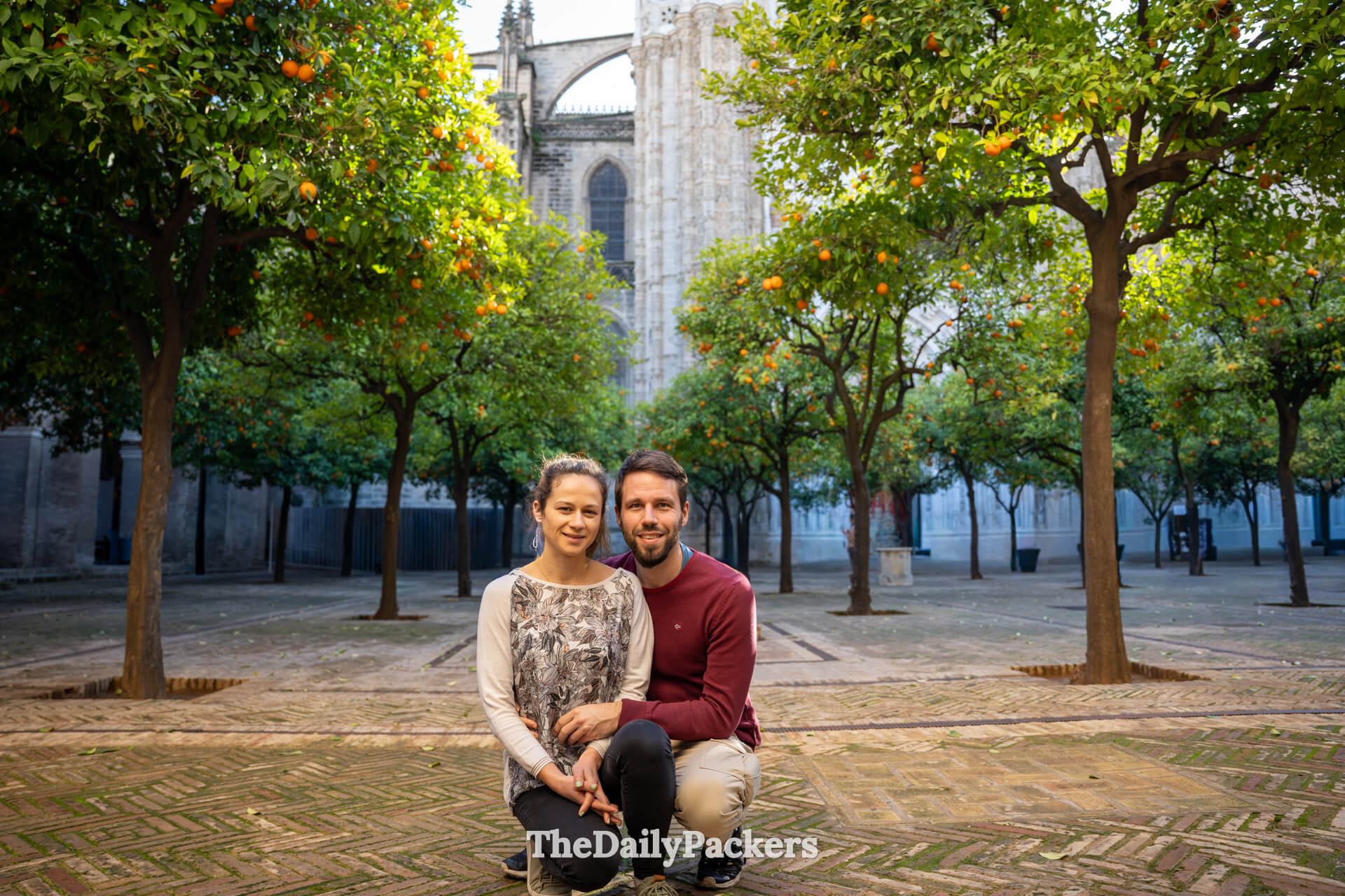 Travel couple sitting together in the peaceful Patio de los Naranjos courtyard at Seville Cathedral.