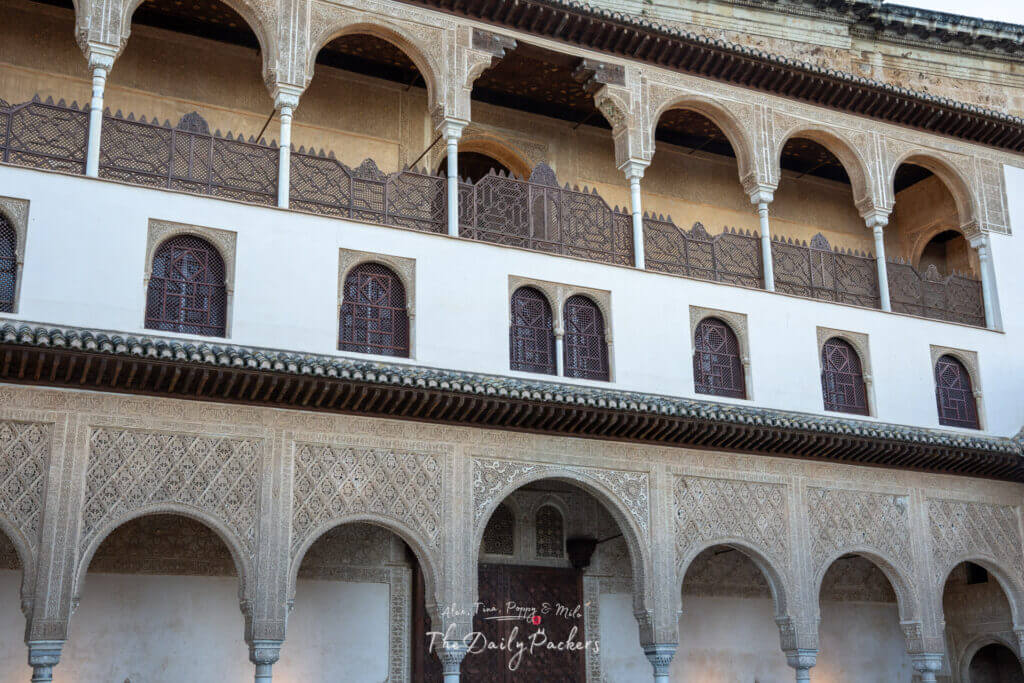 Vue détaillée de la façade du Palais Nasride à l'Alhambra, mettant en valeur les sculptures de stuc ornées, les arches délicates et les motifs architecturaux mauresques traditionnels.
