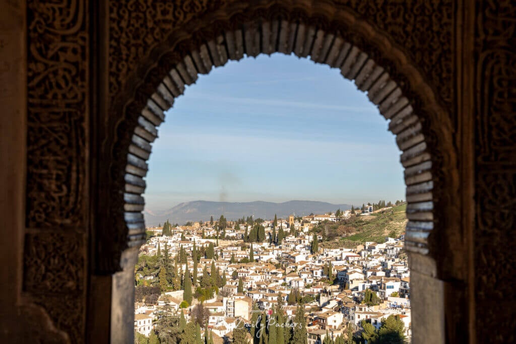 Vue de la ville de Grenade et du quartier de l'Albaicín à travers une fenêtre en arc mauresque de l'Alhambra.
