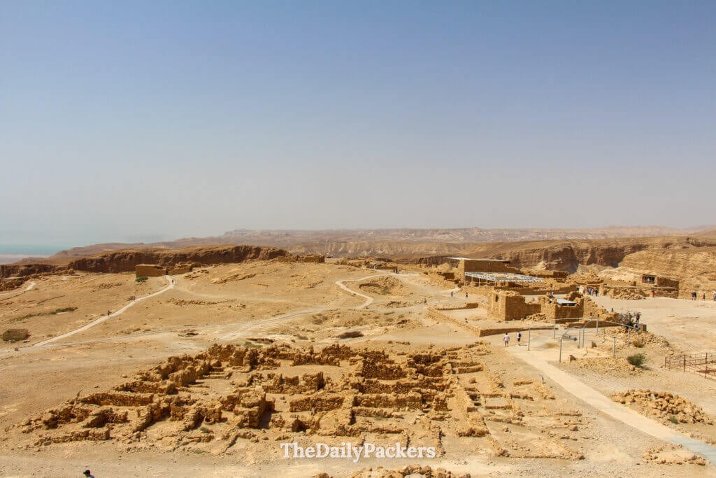 Wide view of Masada fortress ruins with stone foundations, walkways, and the Judean Desert stretching into the distance