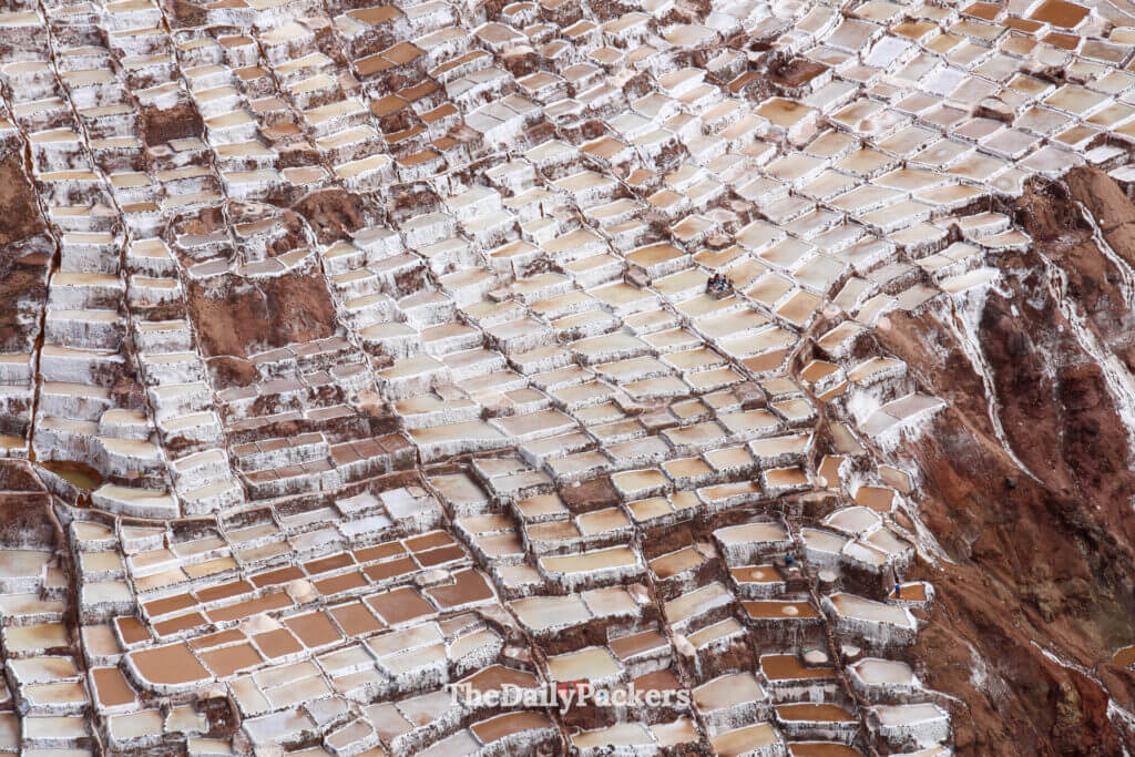Aerial view of the Maras salt mines near Urubamba, Peru, showing thousands of geometric salt pools cascading down the mountainside.