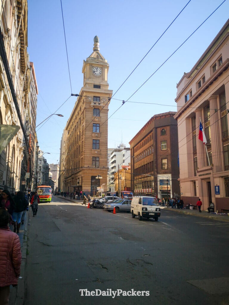 Tour de l'horloge Turri au centre-ville de Valparaíso, s'élevant au-dessus d'une rue animée bordée de bâtiments historiques, de trafic et de piétons traversant le quartier financier.