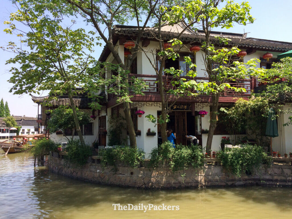 Scène de canal calme à Zhujiajiao avec des maisons traditionnelles aux murs blancs, des balcons en bois et des reflets sur l'eau