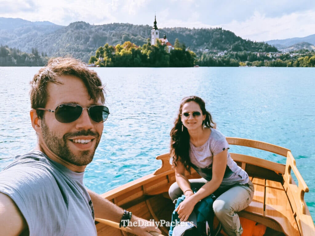 Couple rowing a traditional wooden boat on Lake Bled toward the island