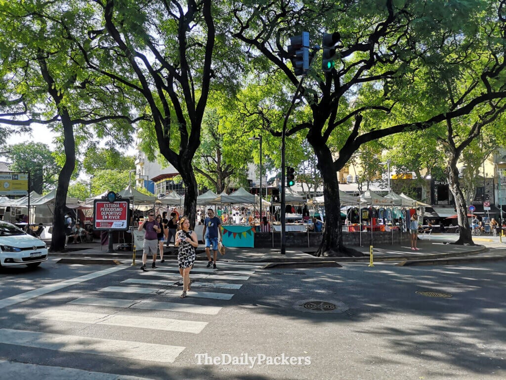 Street market at Plaza Serrano in Palermo, Buenos Aires, with stalls, pedestrians, and shaded streets under large trees