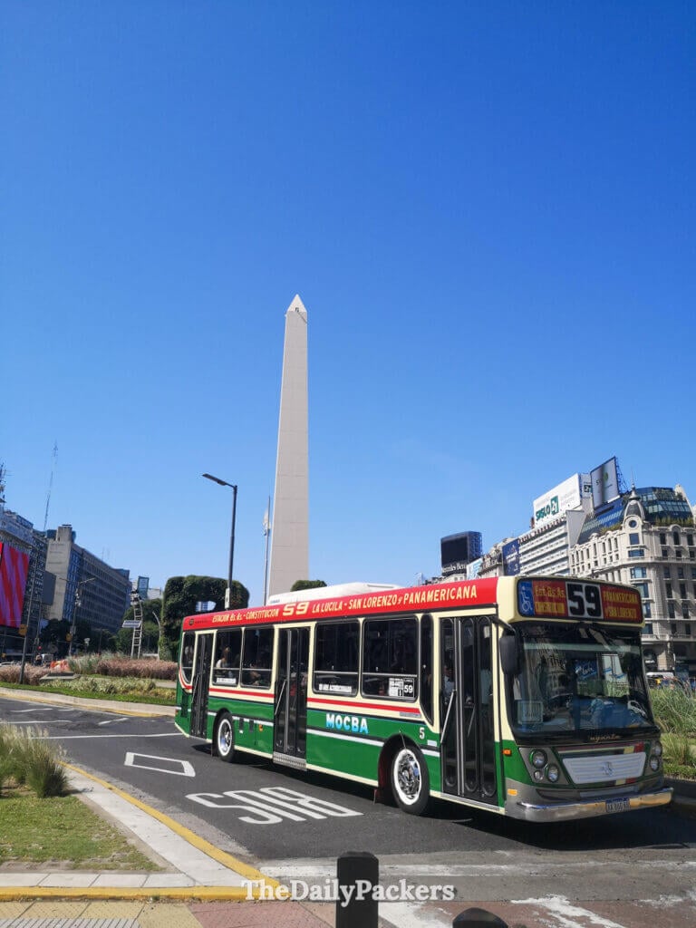 Buenos Aires city bus passing near the Obelisco on Avenida 9 de Julio, combining public transport with the city’s most iconic landmark.