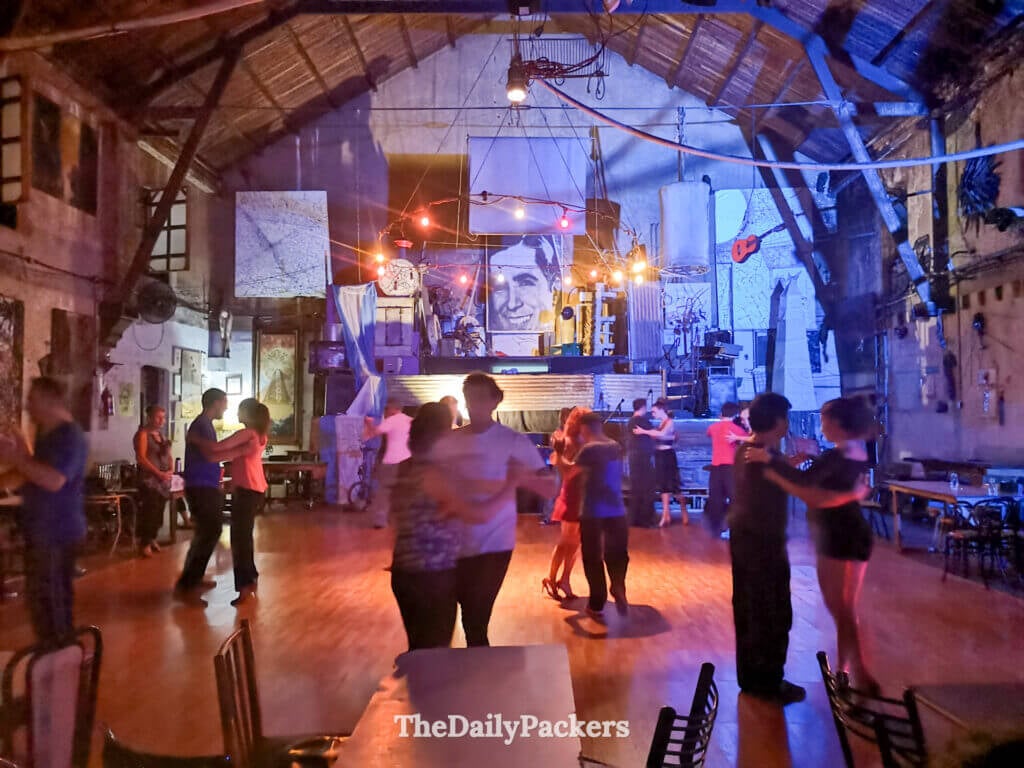 Tango dancing at La Catedral Club in Buenos Aires, with couples practicing on a wooden floor under colorful lights in a historic hall.