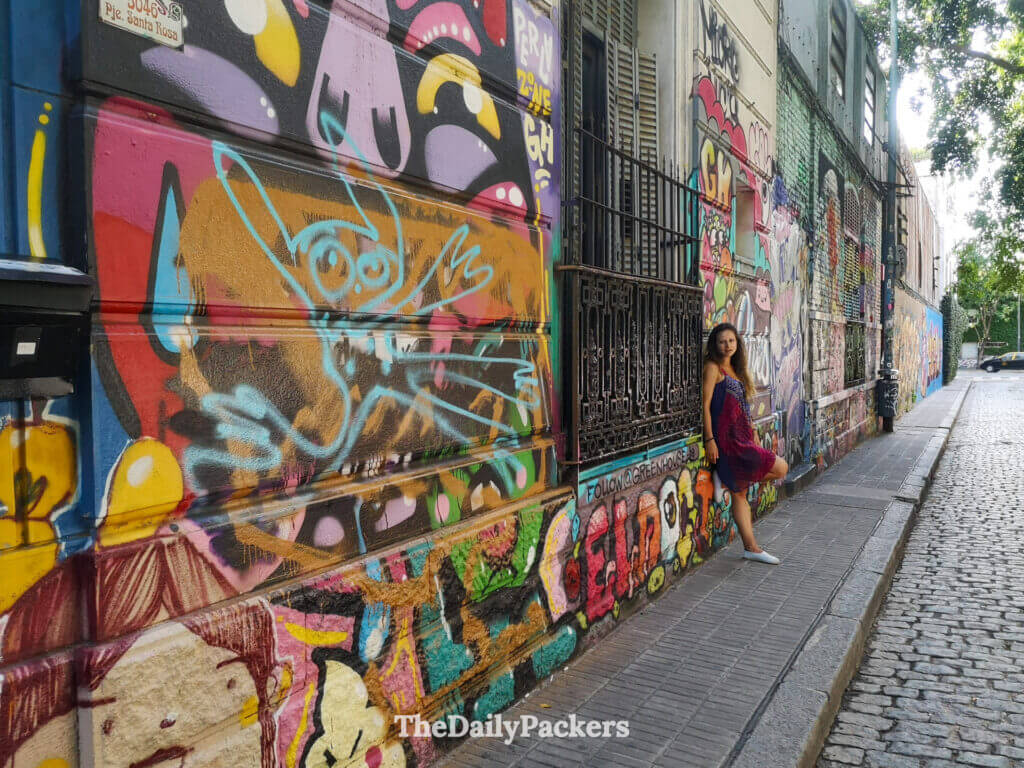Street art-lined sidewalk in Palermo Soho, Buenos Aires, showing vibrant murals and classic architecture near Plaza Serrano.