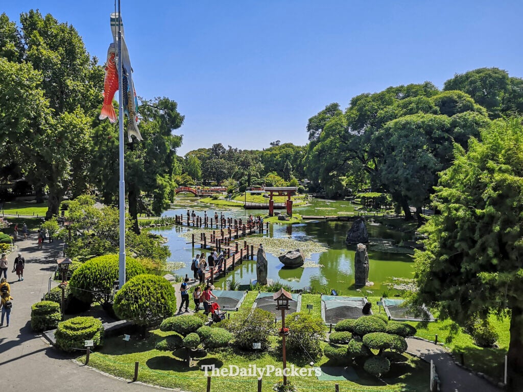 Wide view of the Japanese Garden in Palermo featuring bridges, ponds, sculpted trees, and visitors walking through the peaceful park