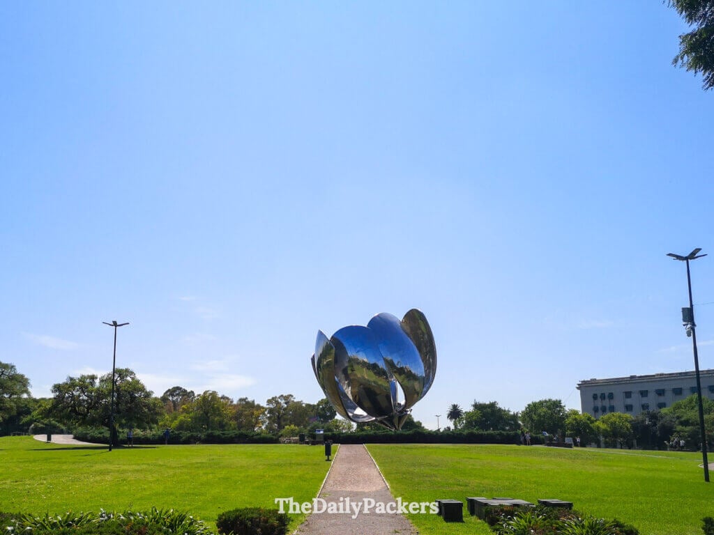 Floralis Genérica sculpture in Recoleta, Buenos Aires, a large metallic flower set in a green park under a blue sky.