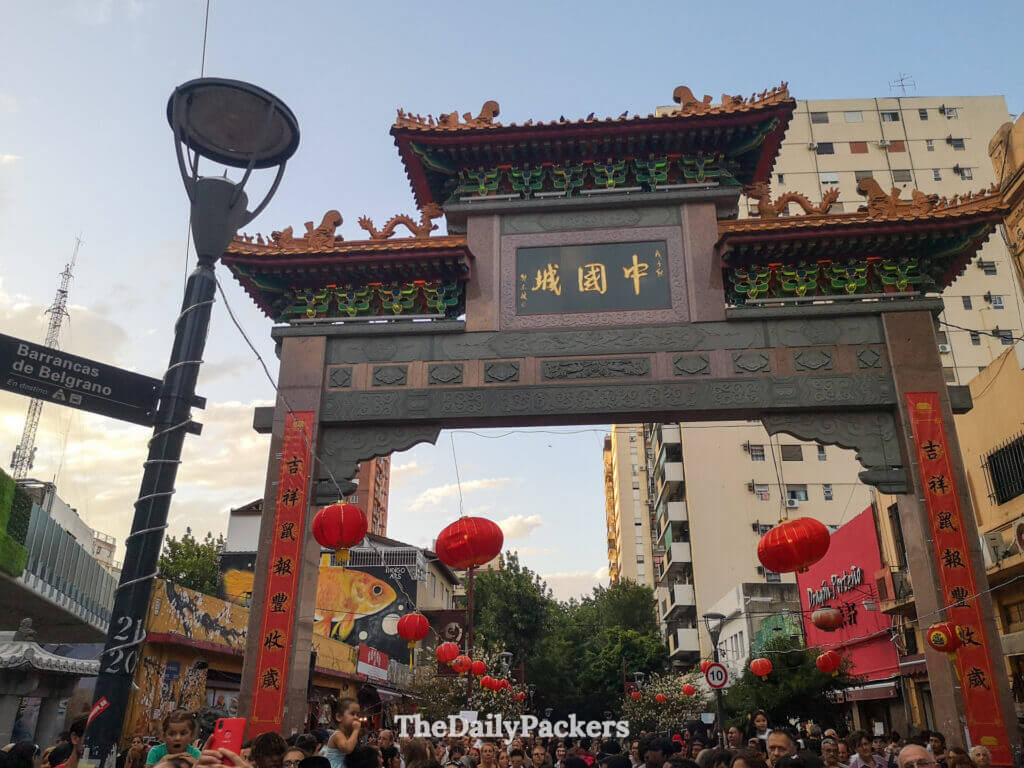 Traditional Chinese gate marking the entrance to Buenos Aires Chinatown, decorated with lanterns and surrounded by crowds.