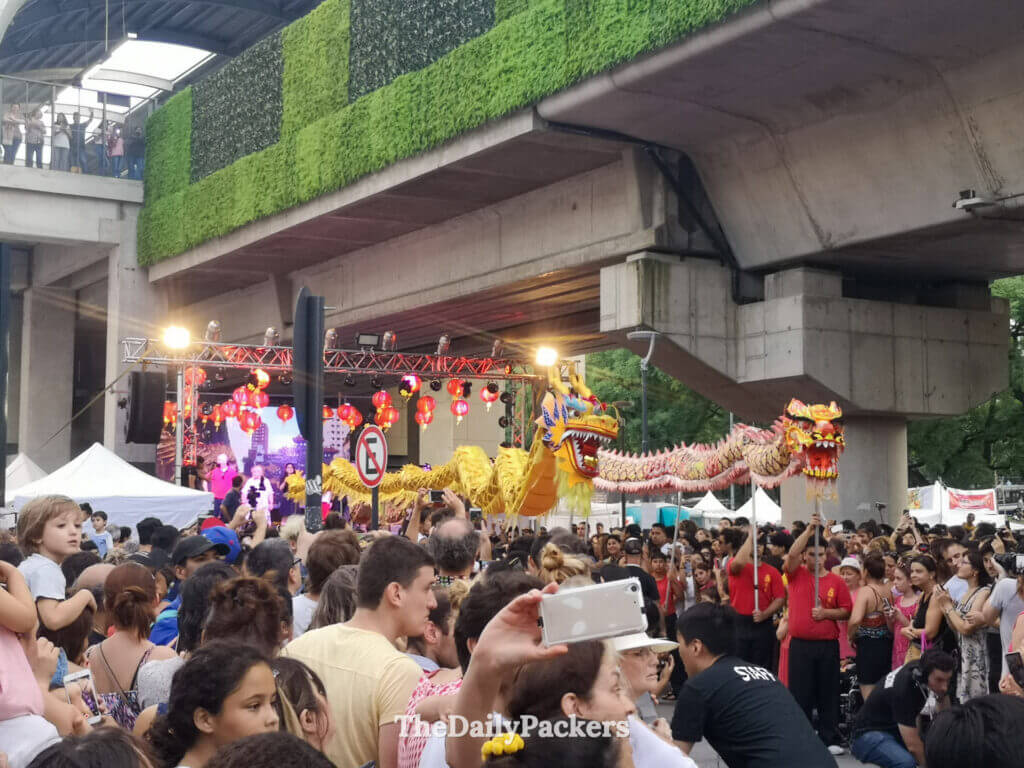Chinese New Year celebration in Buenos Aires Chinatown with a dragon dance, stage performances, and a large crowd under an overpass