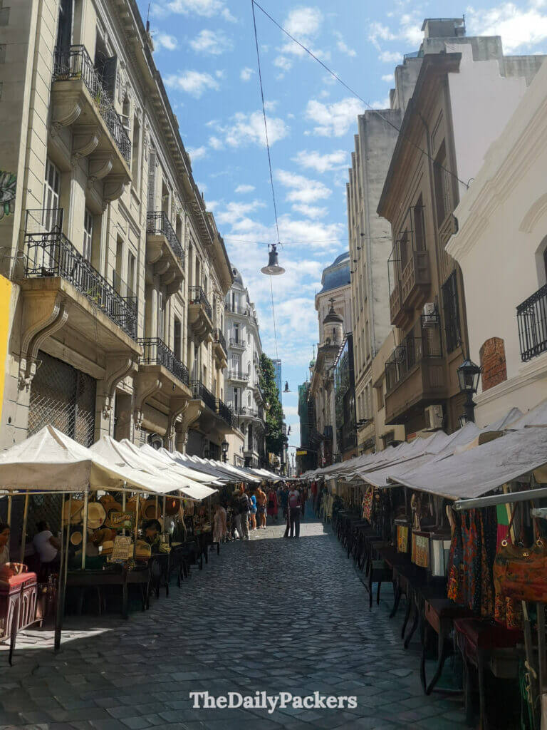 San Telmo Sunday fair along Defensa Street, Buenos Aires, with artisan stalls, cobblestone pavement, and crowds browsing souvenirs.