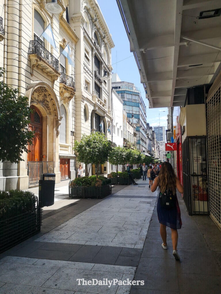 Florida Street pedestrian area in downtown Buenos Aires, lined with historic buildings, shops, and people walking under the midday sun.