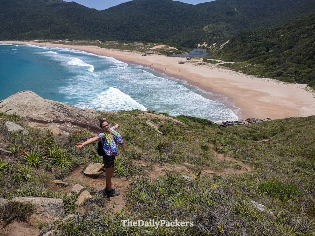 Hiker standing on the Lagoinha do Leste trail just before reaching the beach, with sweeping views over the sandy bay and surrounding hills