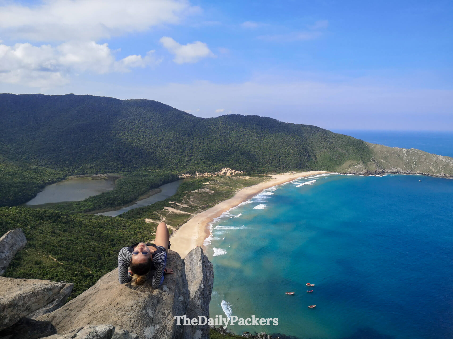 Femme assise au point de vue de Lagoinha do Leste à Florianópolis, encadrée par des falaises spectaculaires et une vue imprenable sur l’océan Atlantique