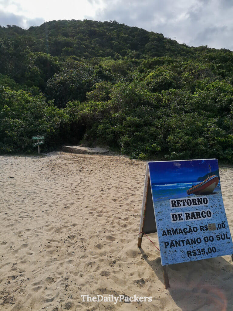 Panneau indiquant le début du sentier à la plage de Lagoinha do Leste à Florianópolis, indiquant les options de retour en bateau et l’accès à Pantano do Sul et Armação