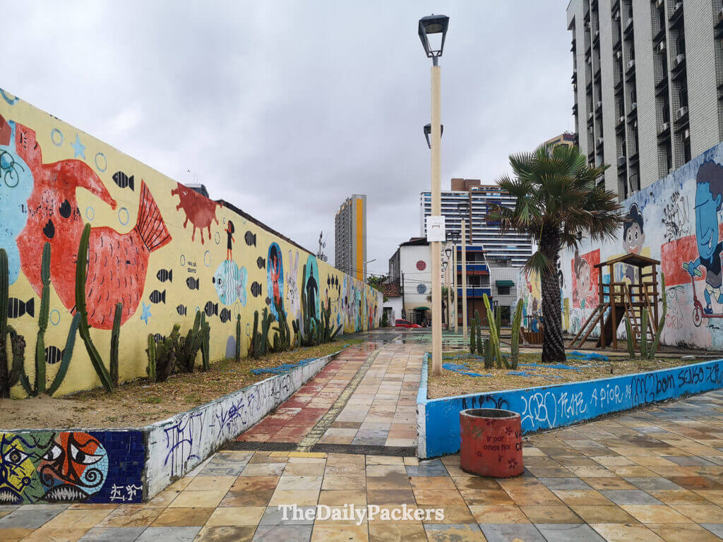 Rainy square in the Dragão do Mar cultural district of Fortaleza, framed by colorful historic buildings and wet cobblestones