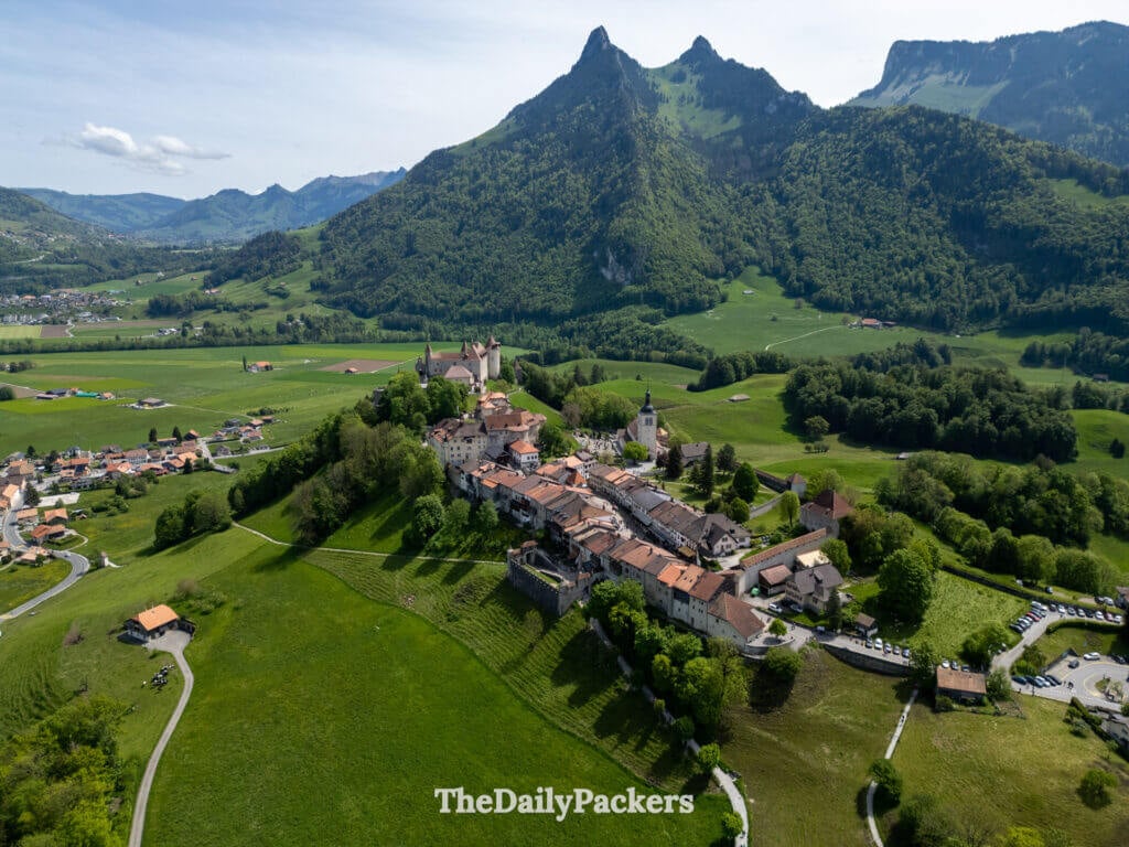 Aerial view of Gruyères medieval old town surrounded by green hills and alpine landscape